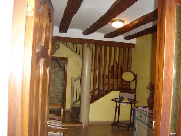 A staircase with wooden balusters, a wooden chair, a small table with a bowl and pinecones, and a mirror on the wall. - Casa rural La Bardena Blanca II (Arguedas)