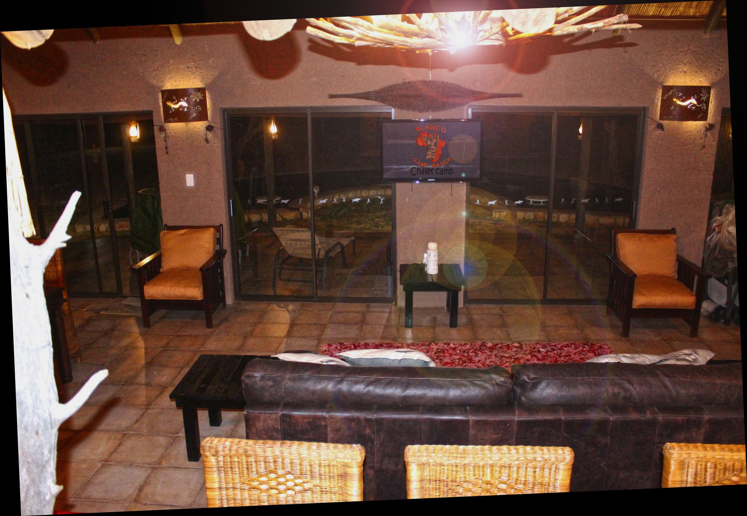 An outdoor seating area with a leather sofa, wicker chairs, and a glass table.