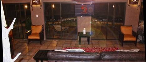 An outdoor seating area with a leather sofa, wicker chairs, and a glass table.