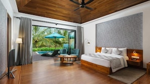 Un dormitorio moderno con techo de madera, una cama grande, un escritorio y vistas a una piscina y follaje.