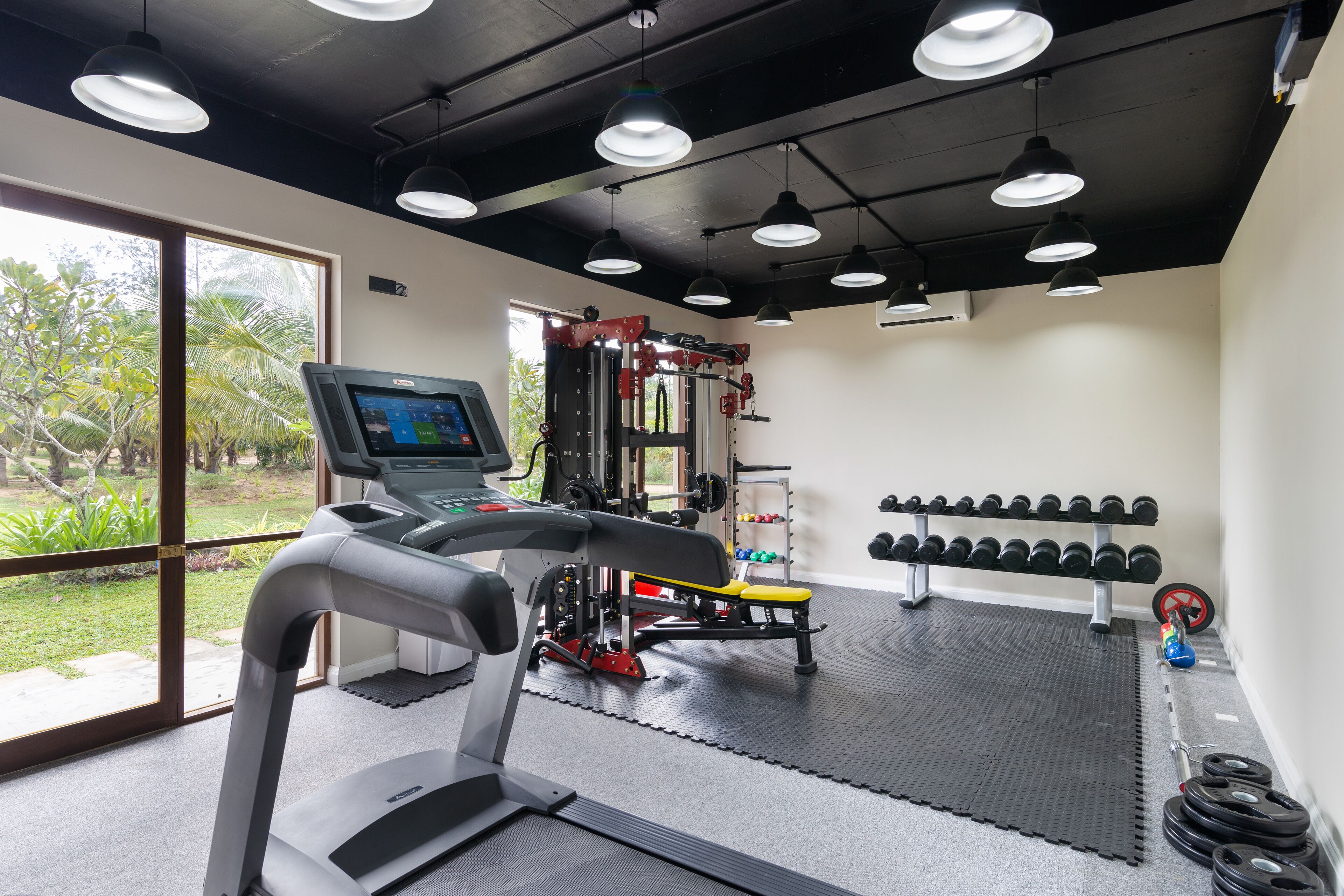 Un gimnasio con cinta de correr, máquinas de pesas y mancuernas.