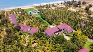 Vista aérea de un resort con varias construcciones, un área de piscina y una playa.