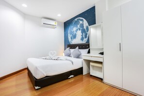 Une chambre d’hôtel avec un lit, un bureau, une armoire et une fresque murale représentant la lune.