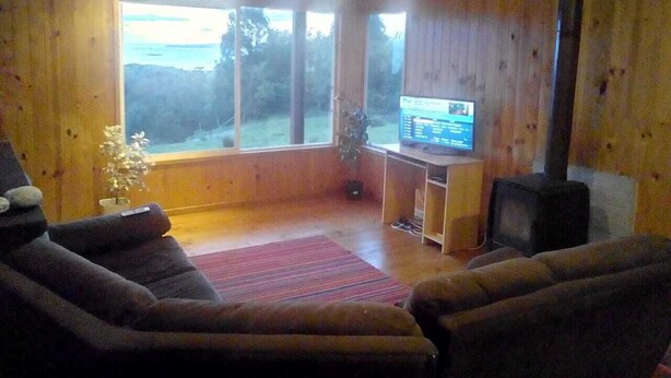 A cozy living room with a fireplace, a television, and a large window overlooking a scenic view.