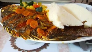 A plate with a whole fish, vegetables, and white rice. - Jaguar Guest House (Kampala)