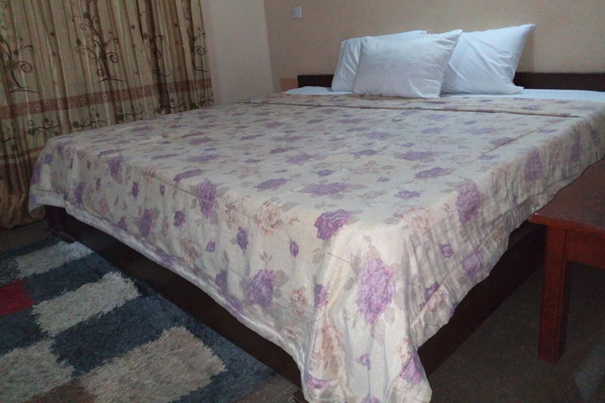 A standard hotel room with a bed, pillows, and a patterned bedspread.