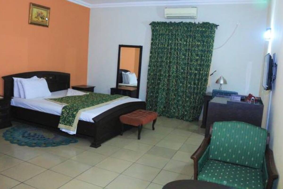 A bedroom with a bed, a chair, a desk, and a mirror.