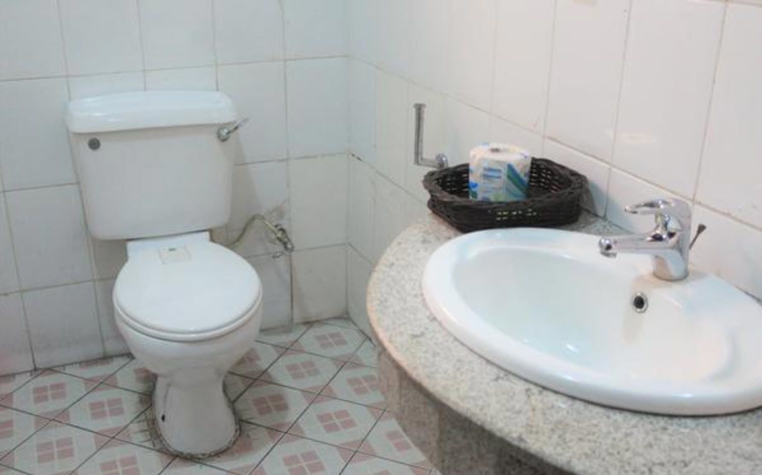A bathroom with a toilet, a sink, and a trash bin.