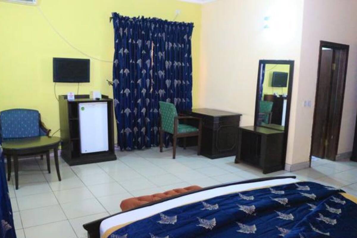 A hotel room with a bed, a desk, a chair, a television, and a curtain.