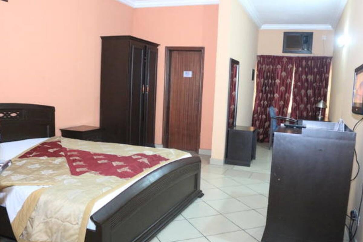A bedroom with a bed, wardrobe, and a desk with a chair.