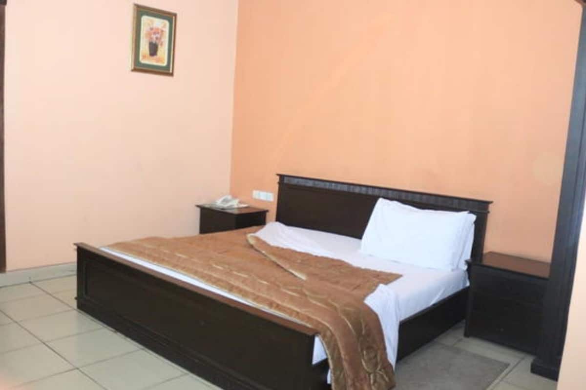 A bedroom with a bed, a nightstand, and a wall-mounted picture.