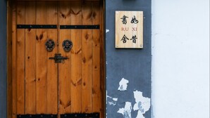 Une porte en bois au design traditionnel, une enseigne avec des caractères chinois et un mur dont la peinture s’écaille.