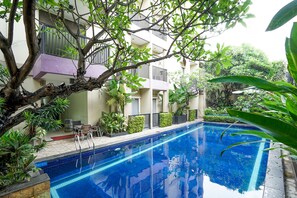 A swimming pool surrounded by greenery and a building with balconies. - Prime Royal Boutique Hotel (Surabaya)