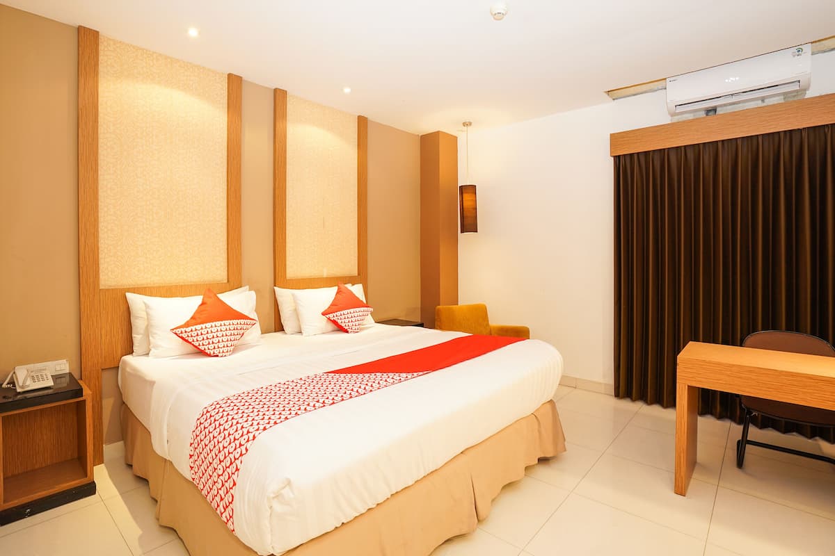 Une chambre d’hôtel avec un grand lit, un bureau et un appareil de climatisation.