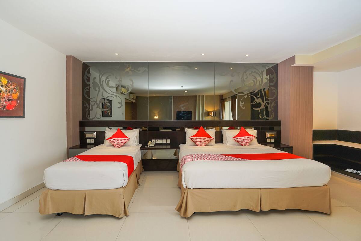 Une chambre d’hôtel avec deux lits, un grand miroir et un design moderne.