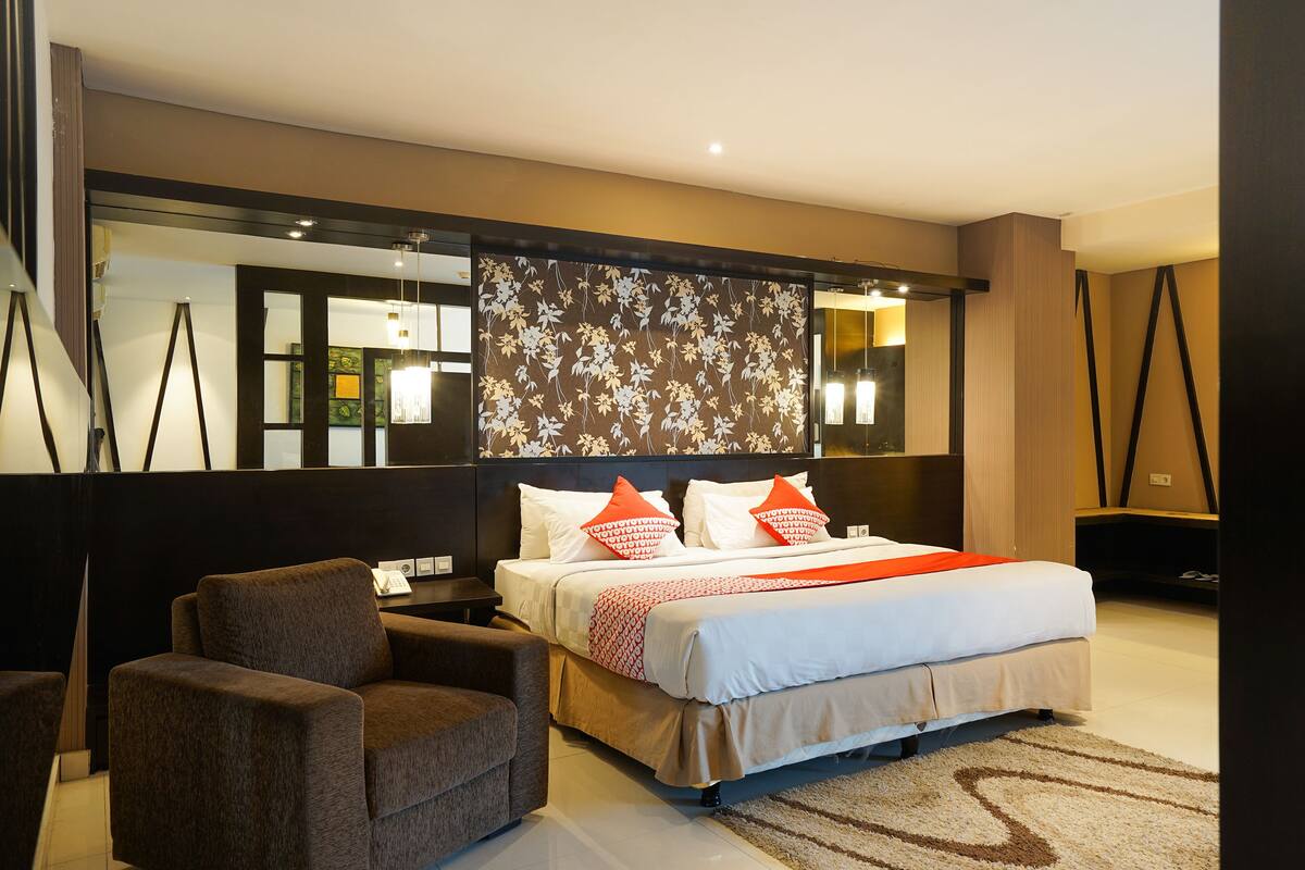 Une chambre d’hôtel moderne dotée d’un grand lit, d’un coin salon et d’un panneau décoratif mural.