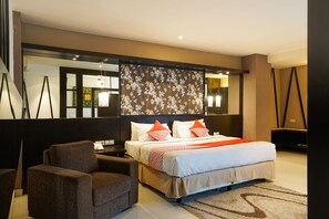 A modern hotel room with a large bed, a seating area, and a decorative wall panel. - Prime Royal Boutique Hotel (Surabaya)