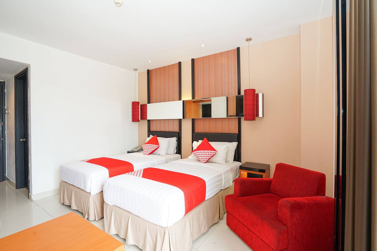 Une chambre d’hôtel avec deux lits, un canapé rouge et une petite table.