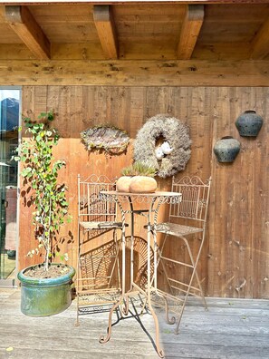 A rustic wooden structure with a metal table and chairs, a potted plant, and decorative wall hangings. - Aparthotel Krösbacher (Fulpmes)