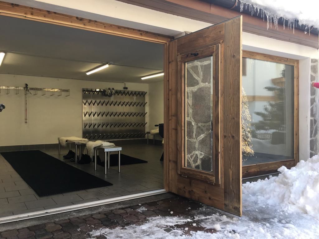 A hotel entrance with a wooden door, a black mat, and a snow-covered ground.