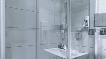 Une salle de bain moderne avec une douche à parois de verre, un lavabo blanc et des murs carrelés.