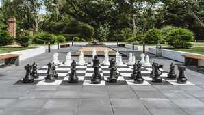 A large outdoor chessboard set up in a park with benches and trees in the background. - Hotel Gustav Stresemann Institut (Bonn)