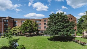 A multi-story brick building with a courtyard featuring green lawns, trees, and outdoor seating. - Hotel Gustav Stresemann Institut (Bonn)