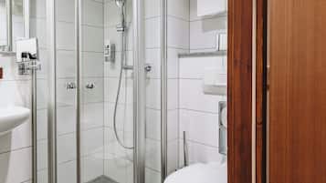 Un baño moderno con ducha de vidrio, inodoro blanco y lavamanos.