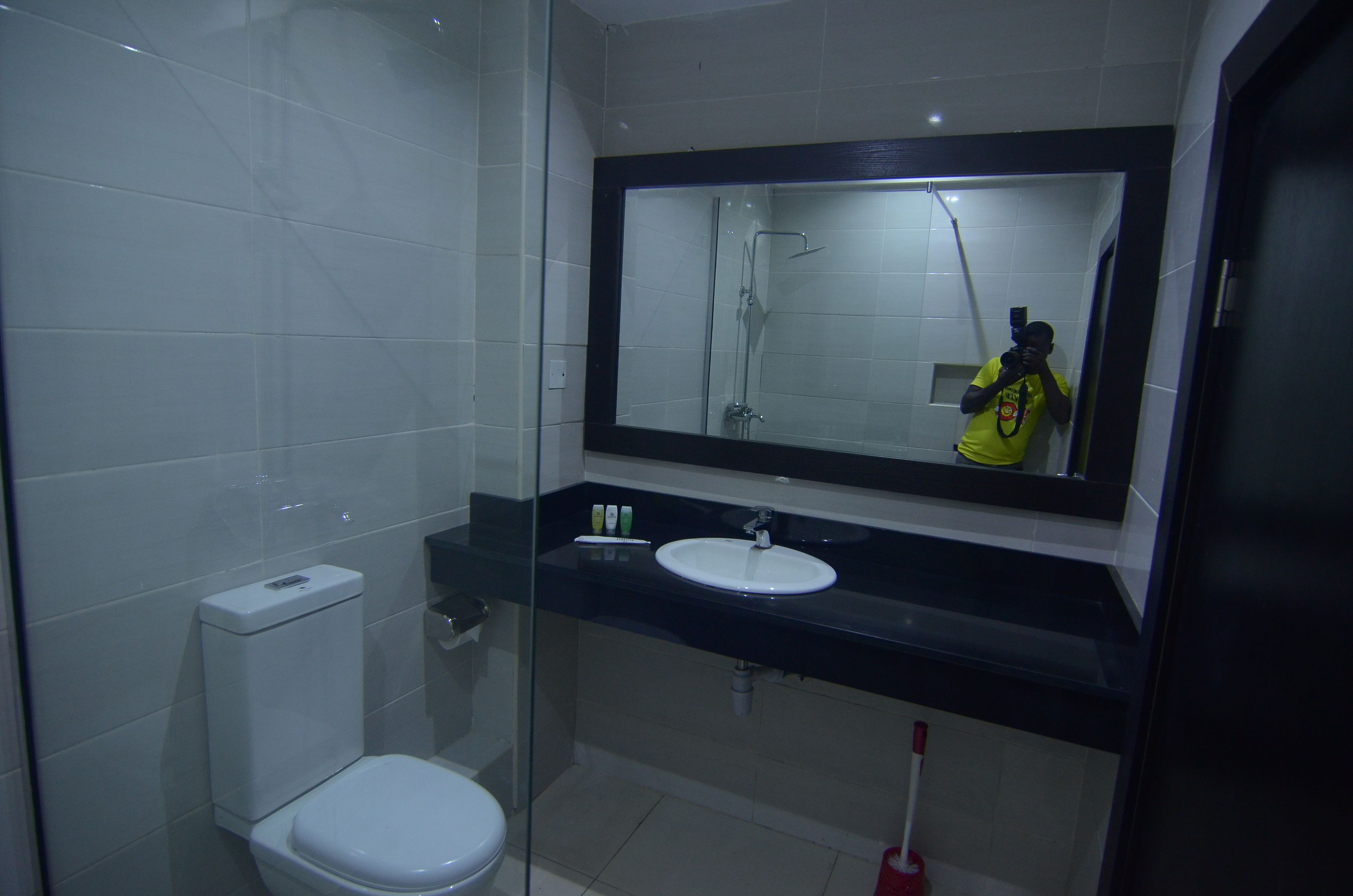 A modern bathroom with a white toilet, a glass-enclosed shower, and a black countertop with a sink.