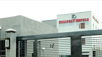 A building with a textured facade and a sign for Hillsbay Hotels.