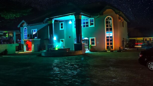 Un bâtiment avec une fontaine devant, une grande fenêtre en arc de cercle et une voiture garée à proximité.