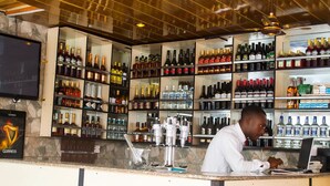 Un espace bar avec des étagères remplies de différentes bouteilles d’alcool et un barman derrière le comptoir.