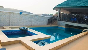 Une piscine dotée d’une terrasse carrelée, d’un espace salon couvert et d’un escalier protégé par une barrière.