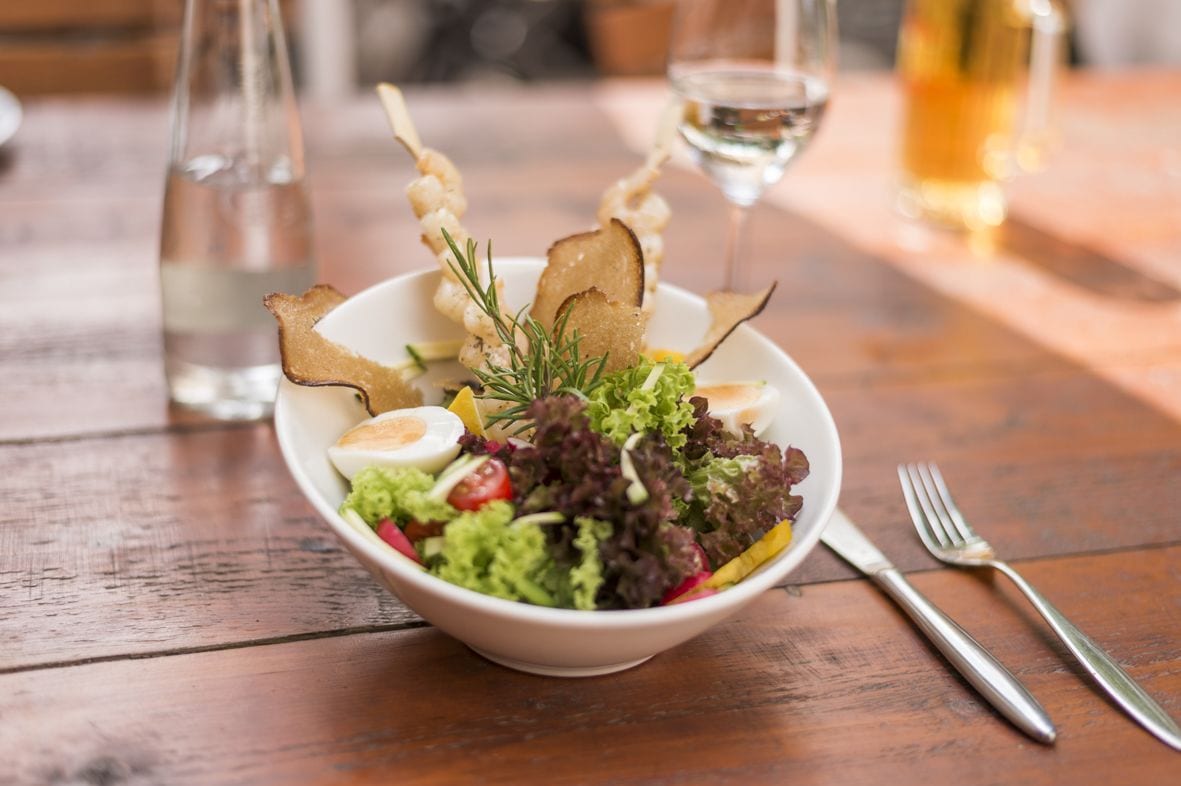 Ensalada con distintos ingredientes y adornos sobre una mesa de madera.