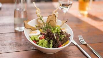 A bowl of salad with various toppings and garnishes on a wooden table.
