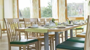 A dining area with wooden chairs and a table set for a meal. - Landgasthaus Hofmann (Oberdachstetten)