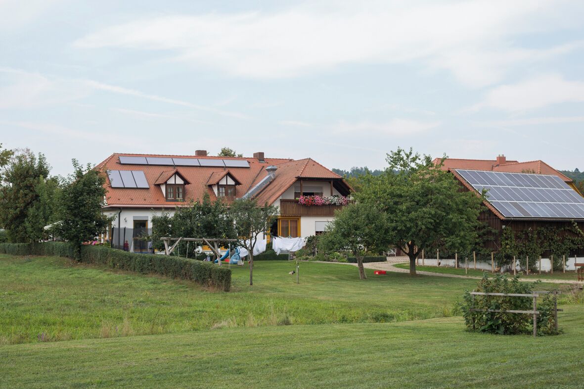 A house with solar panels on the roof, a garden, and a fenced area.