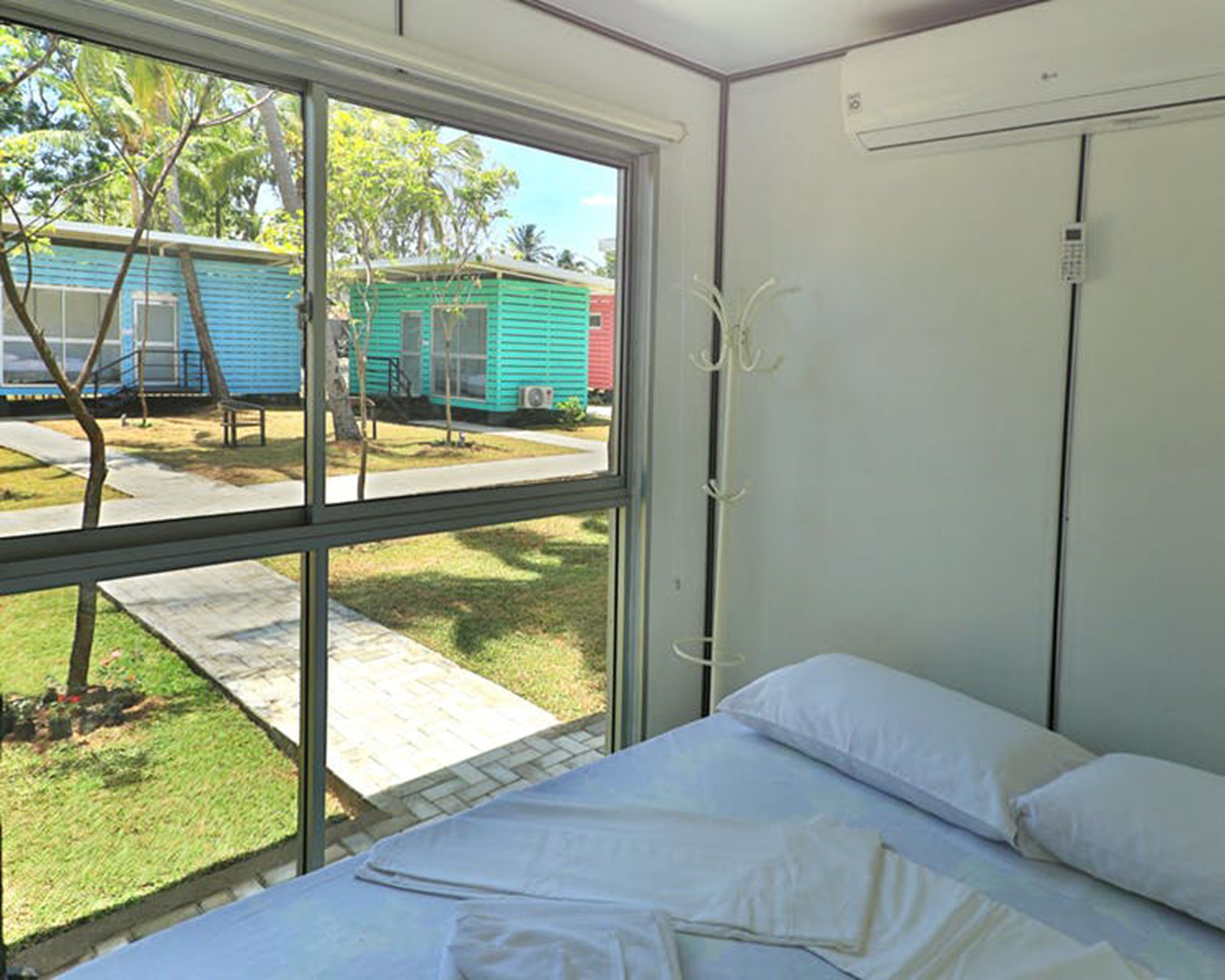 Une chambre avec une grande fenêtre, un lit et un appareil de climatisation.