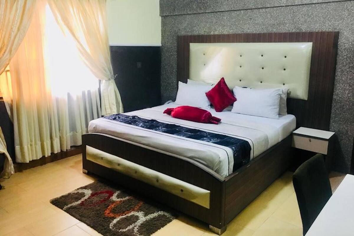 A neatly made bed with a headboard, a bedside table, and a chair.