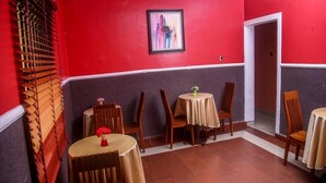 A dining area with red walls, wooden chairs, and round tables. - Le Brigadier Hotel (Lekki)