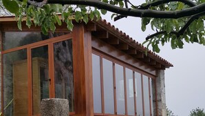 A stone-walled building with large windows and a wooden balcony. - San Larenzu (Aullène)