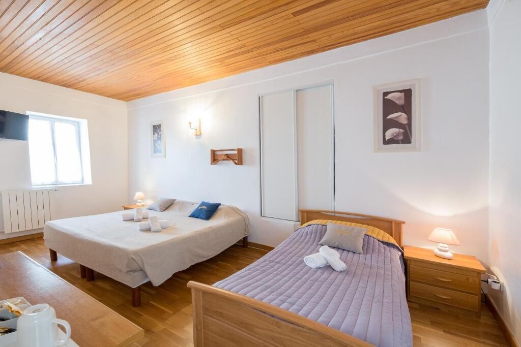 Un dormitorio con dos camas, suelo de madera, un radiador blanco y una ventana.