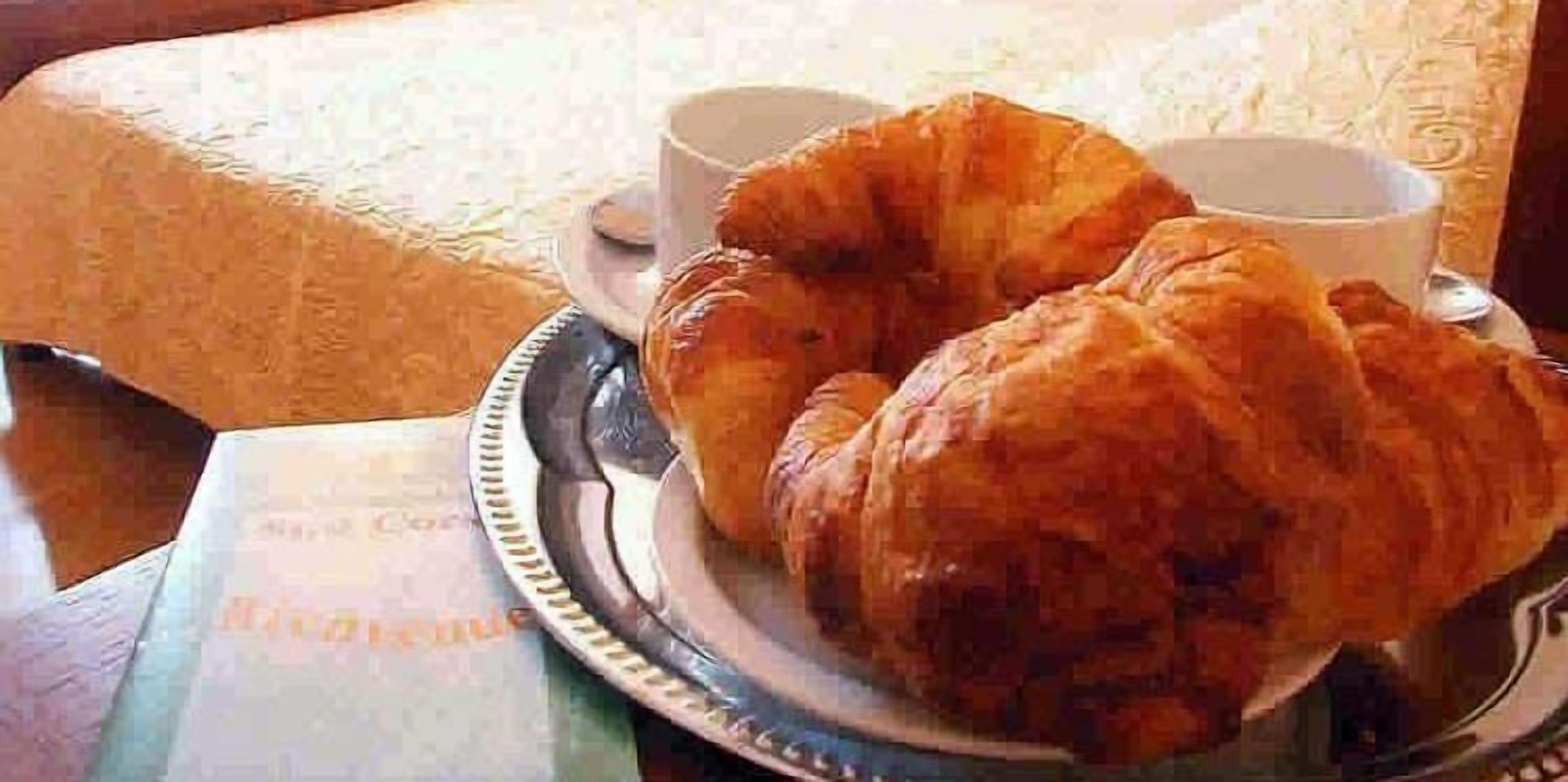 A tray with croissants and two cups of coffee on a table.