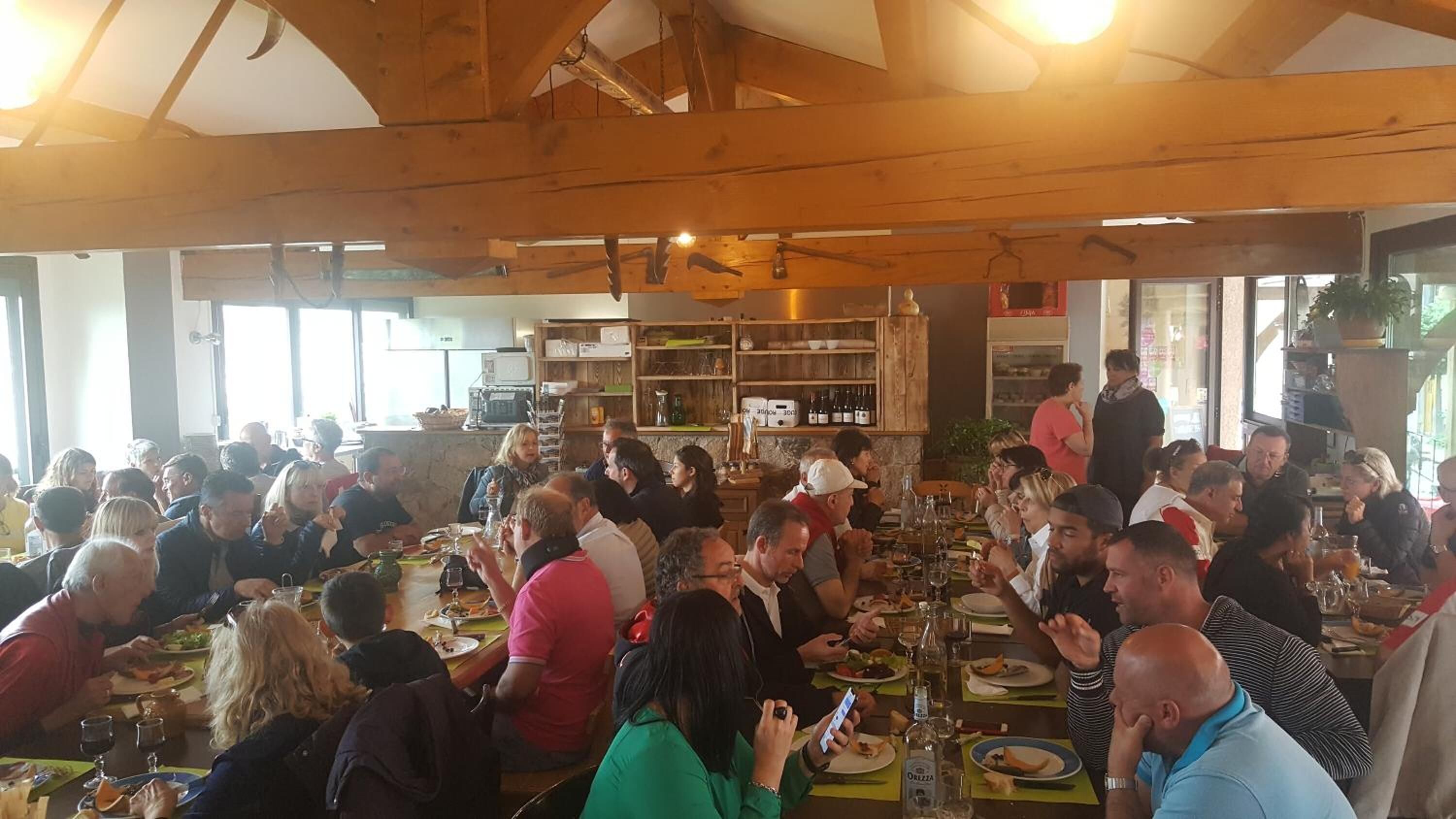 Un restaurant bondé, avec des poutres en bois et de grandes fenêtres.