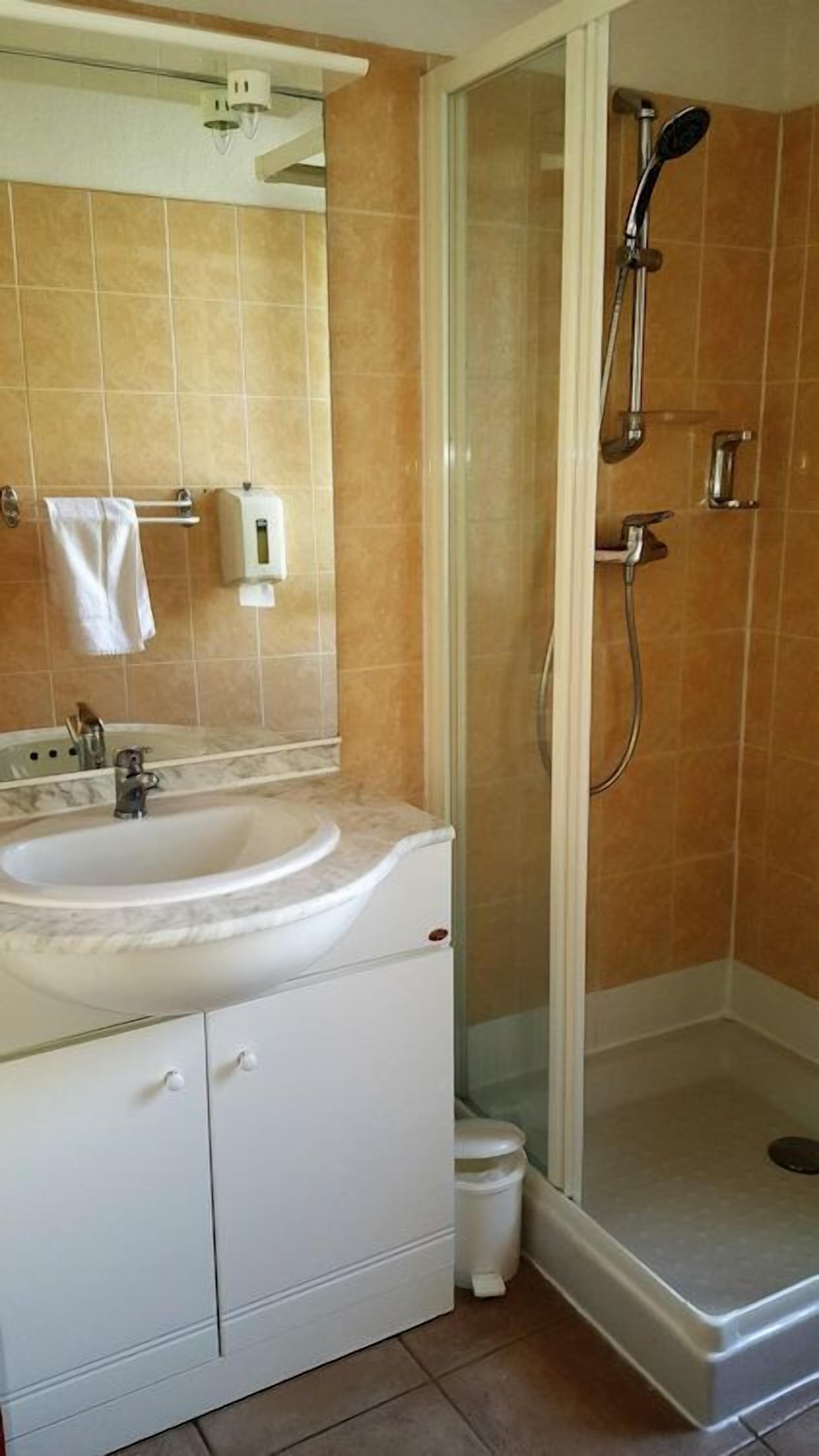 A bathroom with a white sink, mirror, and a glass-enclosed shower area.