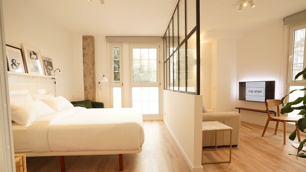 A modern bedroom with a large bed, a desk, and a TV. - The Stay Las Palmas (Las Palmas de Gran Canaria)