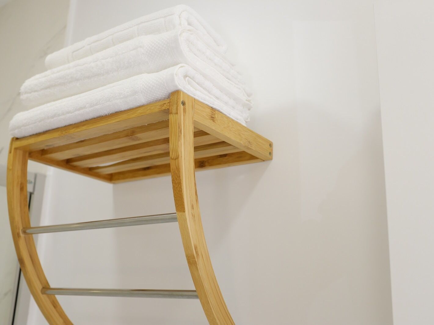 Un portascope legno con asciugamani bianchi impilati sopra.