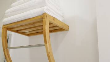 Un portascope legno con asciugamani bianchi impilati sopra.