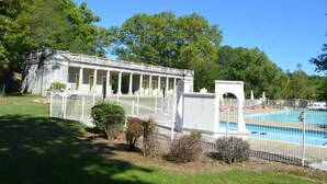 Un bâtiment doté d’une piscine, entouré d’une clôture et de verdure.