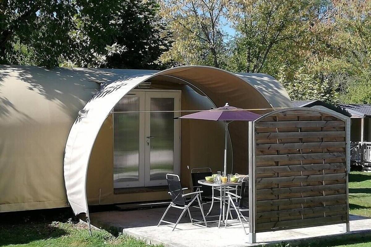 Une petite structure semi-ouverte dotée d’une porte en verre, d’une table de patio et d’une chaise.